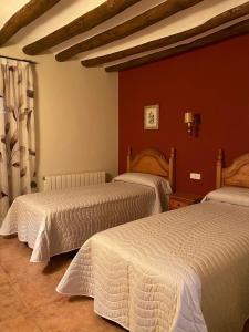 2 camas en un dormitorio con paredes rojas en CASA RUFAS (Sierra de Guara), en Bierge