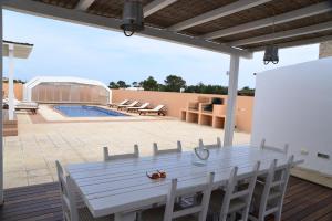 a white table and chairs on a patio with a pool at Casa Can Relax in Es Pujols