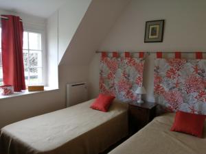 twee bedden in een kleine kamer met rode gordijnen bij Maison d'hôtes "Bienlivien" in Saint-Coulomb