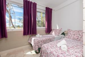 1 dormitorio con 2 camas y una ventana con cortinas moradas en Apartments Villa White House, en Omiš