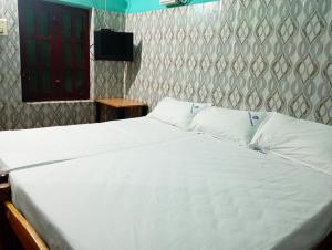 a bedroom with a bed with white sheets and a television at Arputha Lodge in Nāgappattinam