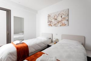 a bedroom with two beds and a painting on the wall at Gospa 58 - 2 bedroom apt in Birżebbuġa