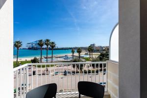 a balcony with a view of the beach and palm trees at Gospa 58 - 2 bedroom apt in Birżebbuġa