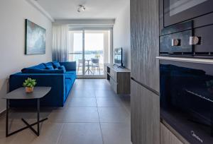 a living room with a blue couch and a table at Gospa 58 - 2 bedroom apt in Birżebbuġa