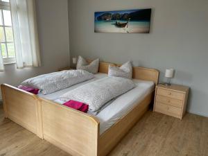 a bed with a wooden frame in a room at Pension Bootshaus in Weißenfels