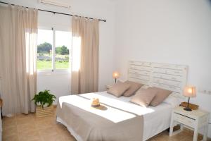 a white bedroom with a bed with a hat on it at Casa Can Relax in Es Pujols +16 photos