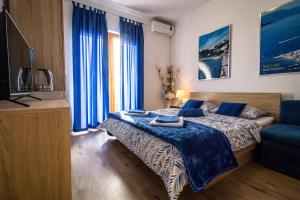 1 dormitorio con cama, TV y cortinas azules en Rooms Bačić en Neum