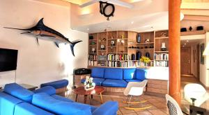 una sala de estar con un sofá azul y un tiburón en la pared en Villa Le Lagon - Vision Luxe, en Bonifacio