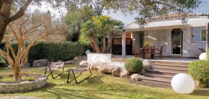 una casa con un patio con sillas y un porche en Villa Le Lagon - Vision Luxe, en Bonifacio