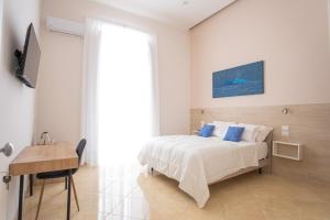ein weißes Schlafzimmer mit einem Bett und einem Schreibtisch in der Unterkunft Leone Suites Toledo in Neapel