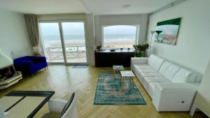a living room with a white couch and a view of the ocean at Beach Apartments Seaview Plus Parking in Zandvoort