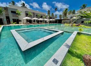 a swimming pool with blue water in front of a building at Villas Manatee - Casa Patacho E002 in Pôrto de Pedras