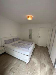 Schlafzimmer mit einem weißen Bett und Holzboden in der Unterkunft Apartments am Moselufer in Bruttig-Fankel