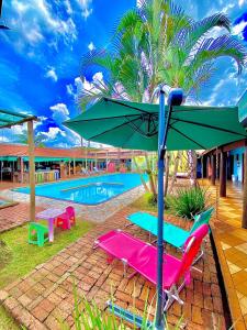 una sombrilla verde y sillas junto a una piscina en O Sole Mio - Hotel Pousada, en Planura