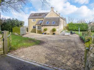 a house with a gravel driveway in front of it at Bills Cottage in Turkdean