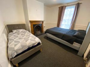 1 dormitorio con 2 camas y chimenea en Southgate Lodge - Single/Twin, Double and Family rooms, en Kings Lynn