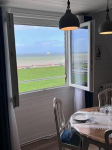 ein Esszimmer mit einem Tisch und einem großen Fenster in der Unterkunft L'air de la mer deux étoiles in Dieppe