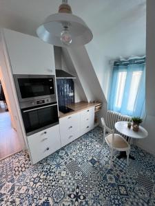 cocina con armarios blancos, mesa y fogones en L'air de la mer deux étoiles, en Dieppe