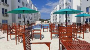 コベニャスにある"Vive el Relax en Caribe Campestre en Coveñas"のプールサイドの椅子とパラソルのグループ