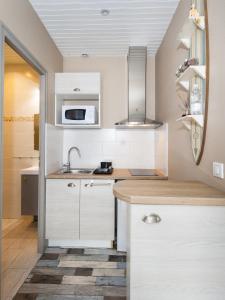 uma cozinha com armários brancos e um lavatório em Le Studio de Noreda em Gujan-Mestras