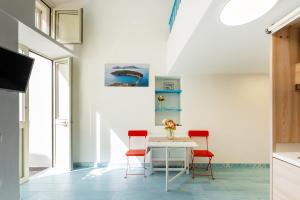 ein Esszimmer mit einem weißen Tisch und roten Stühlen in der Unterkunft La Dependance - Gioia Apartments in Procida