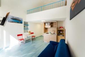ein Wohnzimmer mit einem blauen Sofa und einer Küche in der Unterkunft La Dependance - Gioia Apartments in Procida