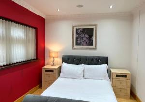 a bedroom with a white bed and a red wall at Luxury Canterbury Holiday Home Sleeps Ten Wifi in Canterbury