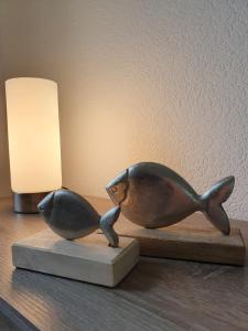 een standbeeld van een vis op een tafel naast een lamp bij Ostfriesland Apartements -FeWo- in Upgant-Schott
