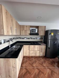 een keuken met houten kasten en een zwarte koelkast bij Apartamento nuevo en Coveñas in Coveñas