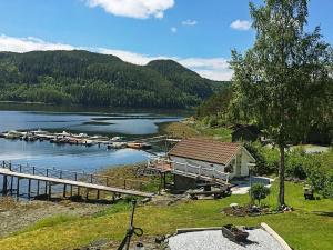 a house on the shore of a lake with a dock at Holiday home Åsenfjord 