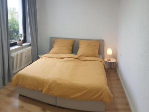 1 dormitorio con 1 cama con sábanas amarillas y lámpara en Studio Apartments in Ruhrgebiet, en Mülheim an der Ruhr