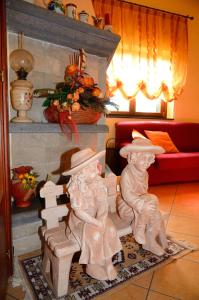 two statues of people sitting on a bench in a living room at B&B Dimora dell' Etna in Milo