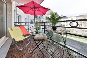 balcón con 2 sillas, mesa y sombrilla en Le Nessel - CENTRE HISTORIQUE - FONDERIE, en Mulhouse