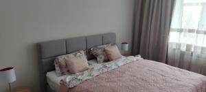 a bedroom with a large bed with pink pillows at Apartaments - Liepu iela in Liepāja