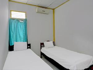 two beds in a room with a window at SPOT ON 92446 Penginapan Aina Syariah 