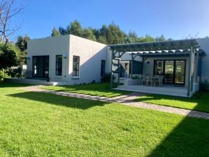 a small white house with a green yard at Tonquani - Knysna (est. 2022) in Knysna