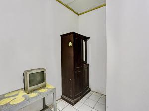 Zimmer mit einem TV und einem Holzschrank. in der Unterkunft SPOT ON 92446 Penginapan Aina Syariah 
