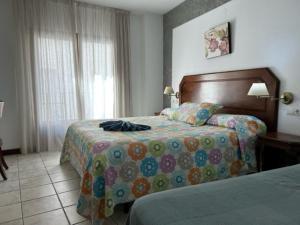 a hotel room with two beds and a window at Hotel Al-Andalus in Torrox