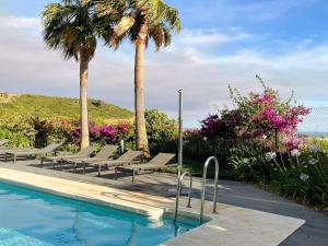 una piscina con tumbonas y palmeras en Superior apartment for golf, sea and nature lovers, en Casares