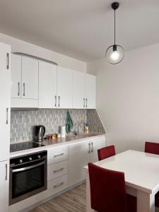 a kitchen with white cabinets and a table with red chairs at Cosy Apartment with a Great View in Pristina