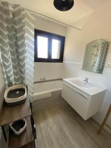 uma casa de banho com um lavatório, uma banheira e um espelho. em Logement entier dans maison - Passy - 6 personnes em Passy