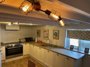 a kitchen with white cabinets and a black stove top oven at The North Wales Gathering - Hot Tub & Sleeps Up To 16 in St Asaph