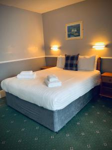 a bedroom with a large bed with towels on it at Palm Court B&B in Ilfracombe