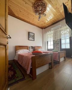 1 dormitorio con cama y techo de madera en As e vogël, As e madhe en Ersekë