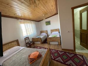 a bedroom with two beds and a wooden ceiling at As e vogël, As e madhe in Ersekë