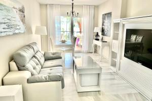 ein weißes Wohnzimmer mit einem Sofa und einem Tisch in der Unterkunft MI CAPRICHO 9B BEACHFRONT- Apartment with sea view - Costa del Sol in Mijas Costa