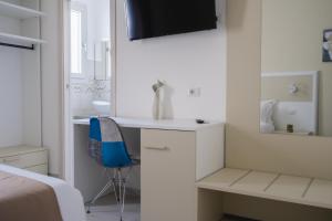 Habitación blanca con escritorio y silla azul en VeMi Affittacamere, en Posada