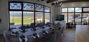 een lange tafel met stoelen in een kamer met ramen bij Vila Marina Ilkoni at Jrebchevo dam in Kriva Krusha