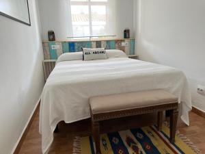 a bedroom with a bed with a white blanket and two chairs at Casita de Bolonia in Bolonia