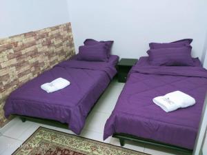 Kuantan Homestay Best Facility Wifi BBQ Viu في كُوانتان: سريرين في غرفة مع ملاءات أرجوانية ومناشف